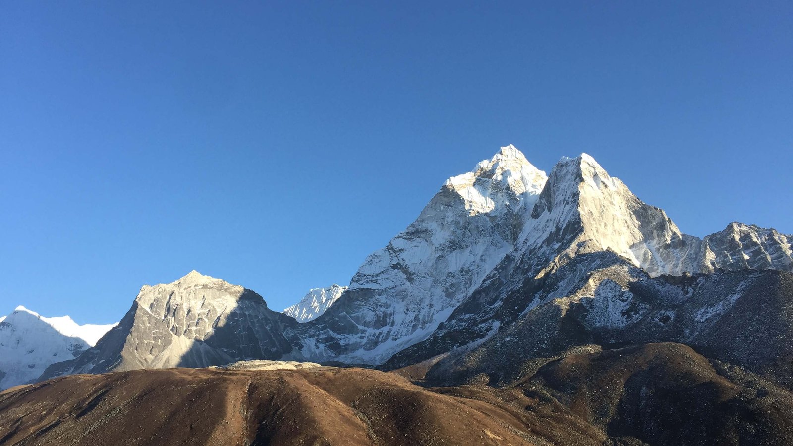 Mount Ama Dablam rising above the Himalayan foothills in the Everest Region of Nepal, with a crystal-clear sky and dramatic snowy ridges