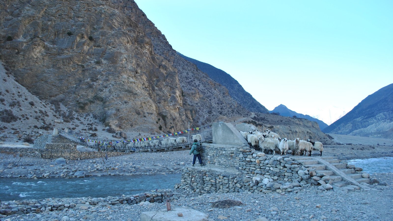 A scenic view of the Kali Gandaki Corridor, showcasing the deep river gorge flanked by steep cliffs and Himalayan peaks, with traditional villages and winding trails along the valley.