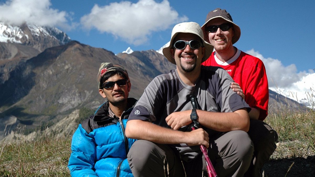 Trekkers relaxing along the Annapurna Circuit Trek with panoramic views of the Himalayas and serene alpine landscapes.