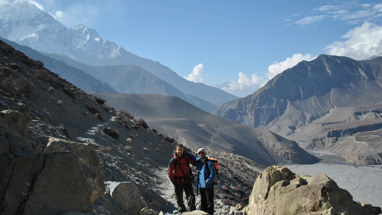Trekkers hiking the Annapurna Circuit Trail surrounded by snow-capped Himalayan peaks, traditional villages, and alpine landscapes in Nepal