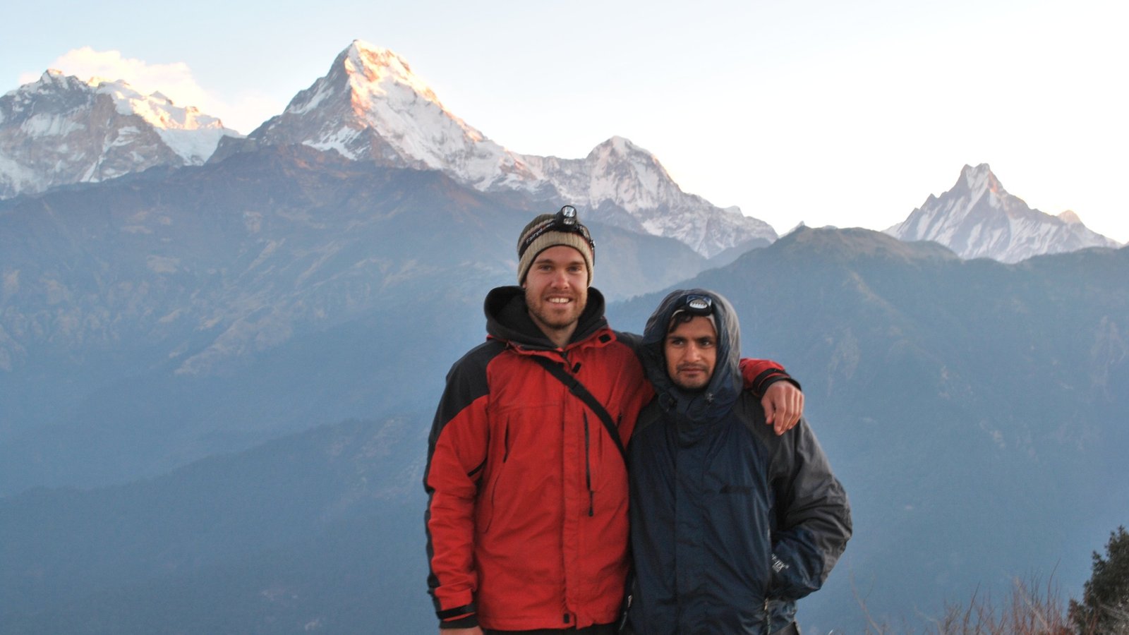 Trekkers standing at the summit of Poon Hill, surrounded by panoramic Himalayan mountain views during sunrise.
