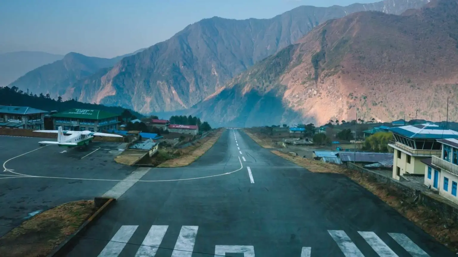 Everest Base Camp Trek gateway Lukla Airport runway with plane and Himalayan sunrise scenery