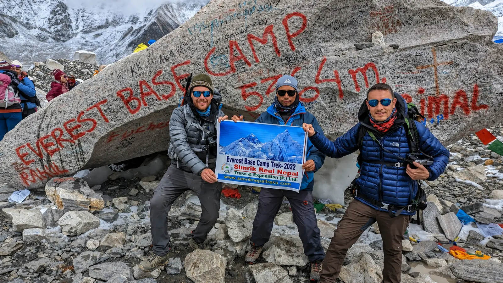 Everest Base Camp trek (5364m) with trekkers holding Simrik Real Nepal banner, Khumbu Glacier, Himalayas Nepal adventure trekking scene