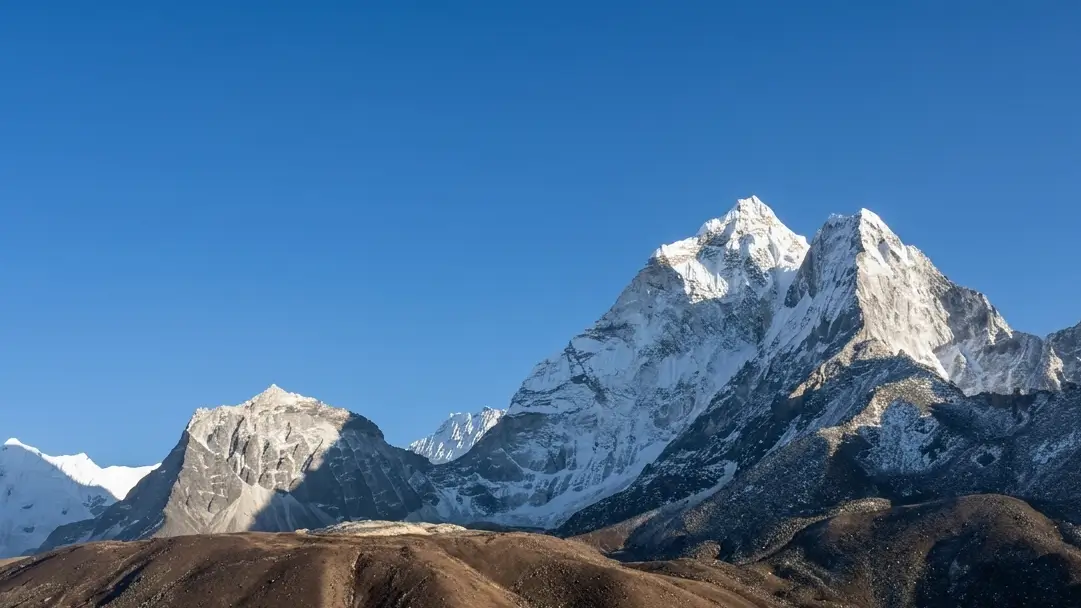 Trekkers navigate rugged trails beneath the snow-capped Himalayas.
