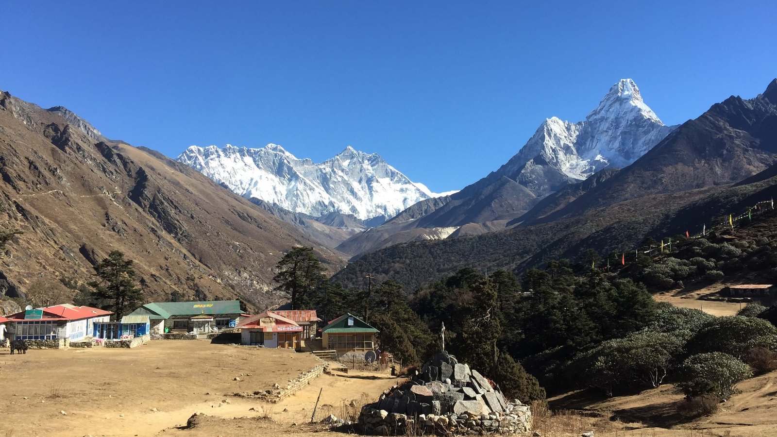Clear day on the Everest View Trek with traditional houses and snowy Himalayan peaks.