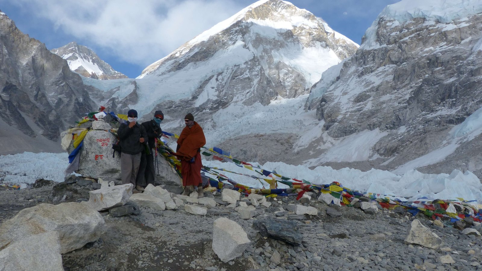 A group of New Zealand trekkers standing at Everest Base Camp with Mount Everest and Khumbu Icefall in the background.