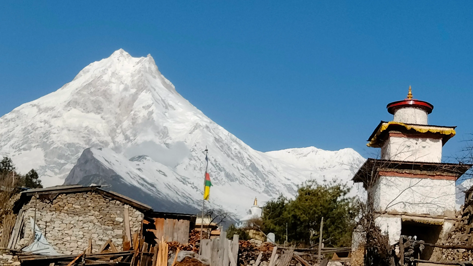 Mount Manaslu towering above Lho village houses Manaslu Circuit Trek iconic scene