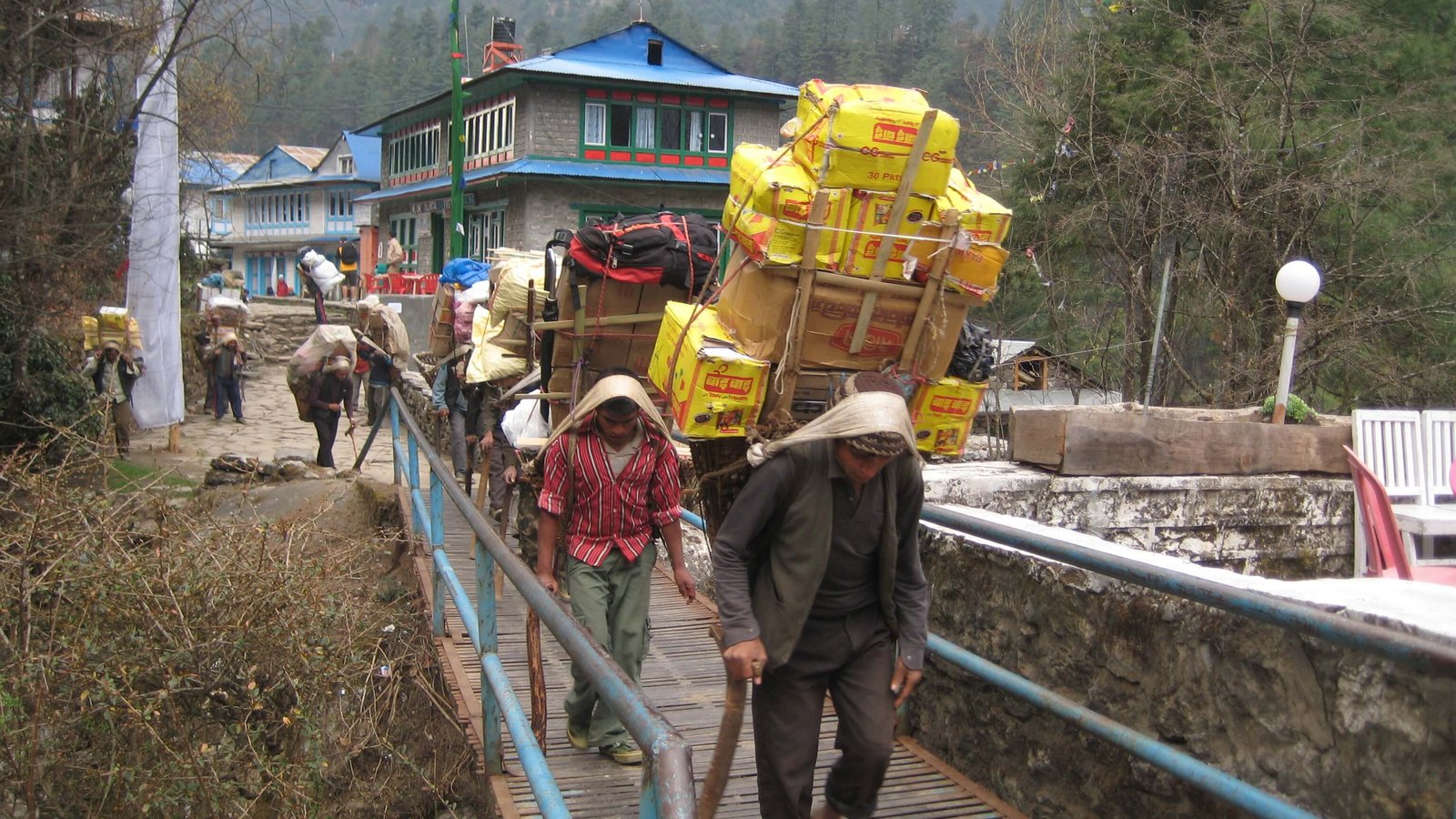 Sherpa and Nepali porters carrying heavy loads for trekkers in the mountain villages of the Everest Region, Nepal