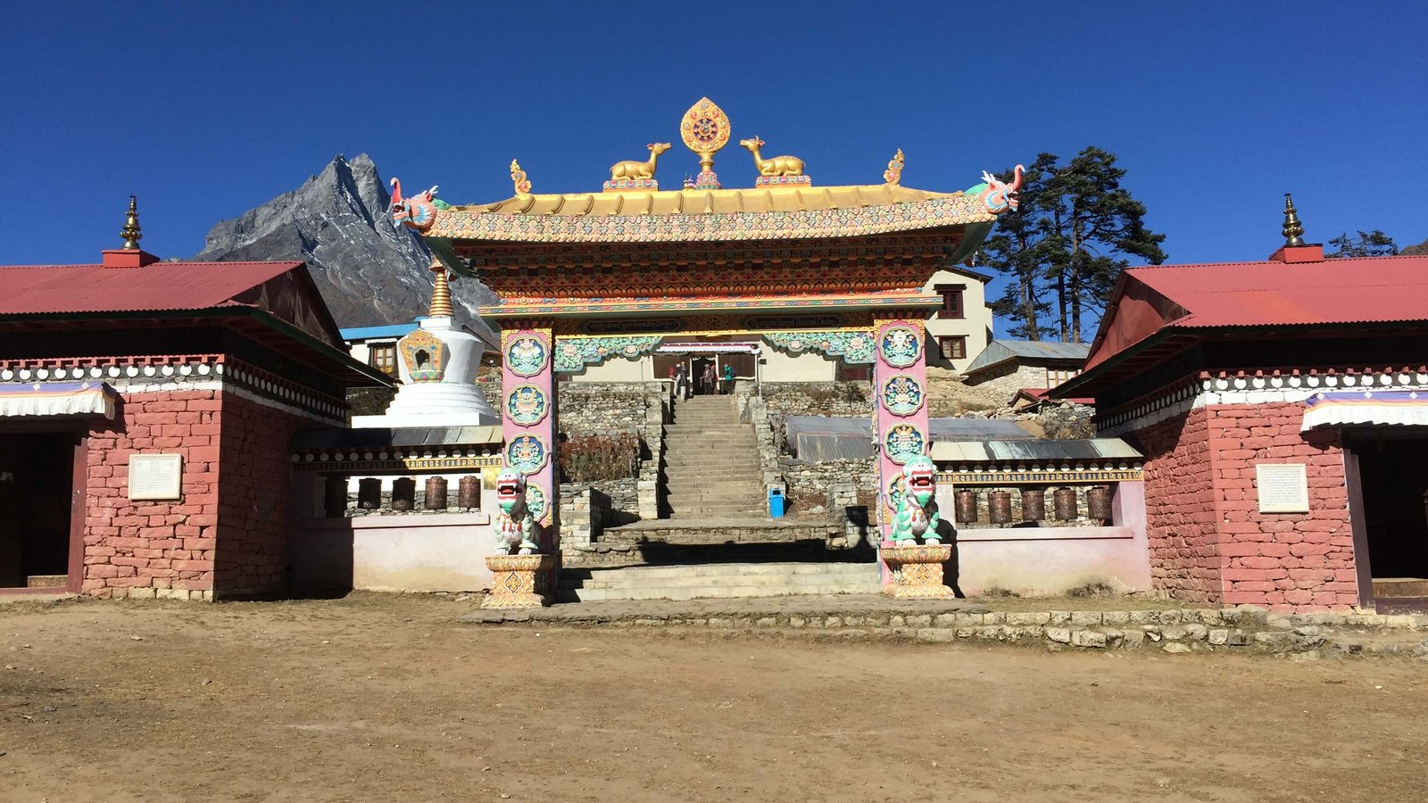 Tengboche Monastery in the Everest Region of Nepal with clear blue sky, prayer wheels, and Himalayan peak in the background