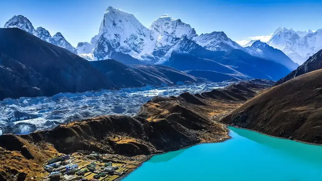 Panoramic view of turquoise Gokyo Lake surrounded by snow-capped Himalayan peaks in Nepal.